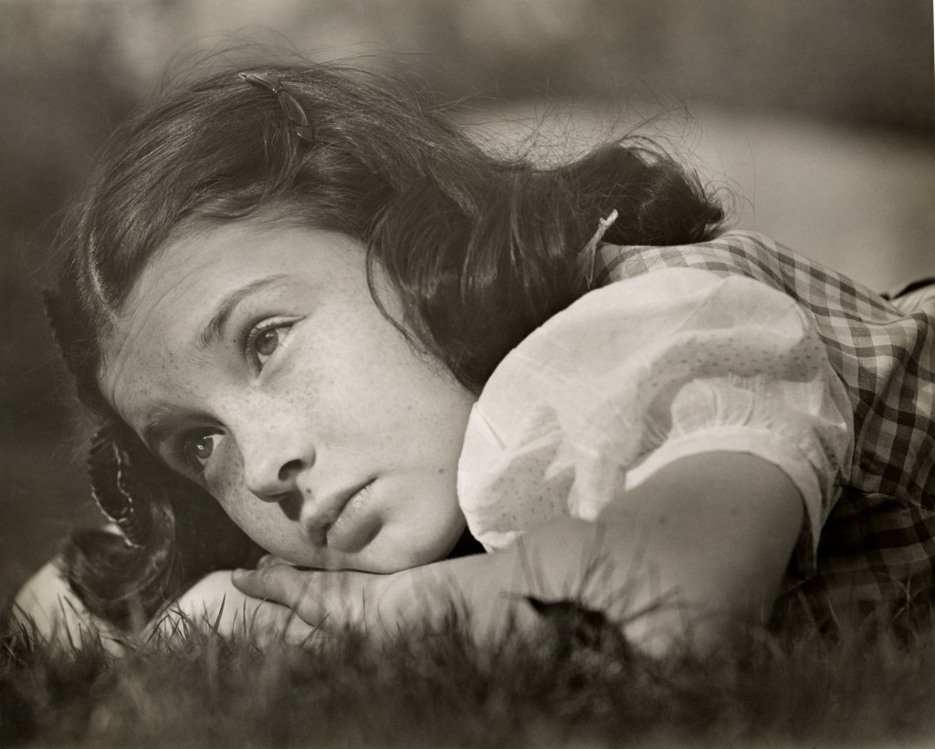 Sad young girl laying on the grass